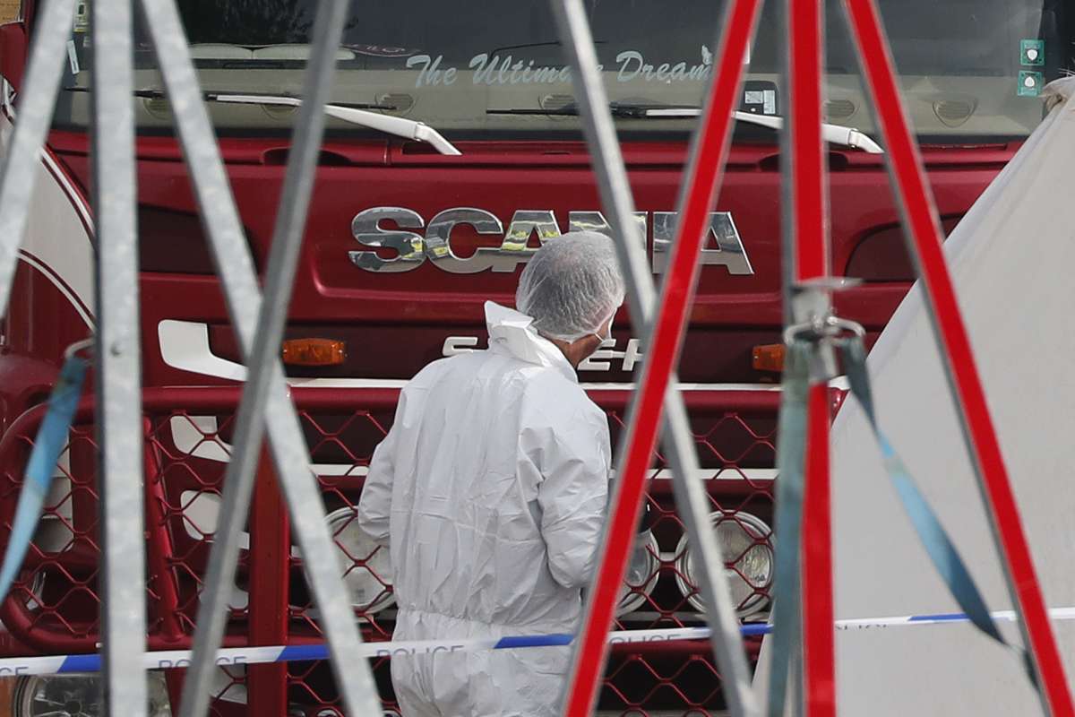 Police forensic officers attend the scene after a truck, in rear, was found to contain a large number of dead bodies, in Thurrock, South England, early Wednesday Oct. 23, 2019. Police in southeastern England said that 39 people were found dead Wednesday inside a truck container believed to have come from Bulgaria.